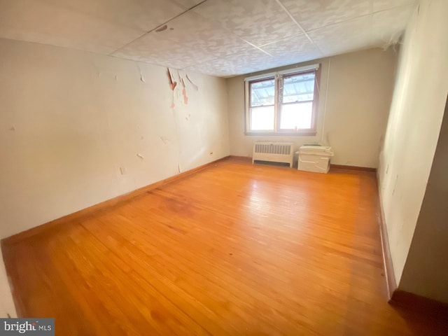 unfurnished room featuring light wood-type flooring, baseboards, and radiator heating unit