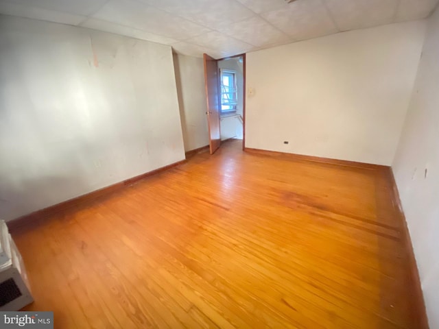 unfurnished room with light wood-style floors, a paneled ceiling, and baseboards