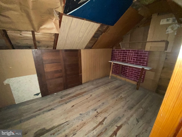 interior space featuring vaulted ceiling, wood walls, and hardwood / wood-style flooring