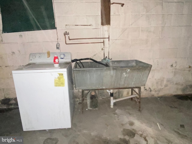 interior space with concrete block wall, laundry area, washer / clothes dryer, and a sink