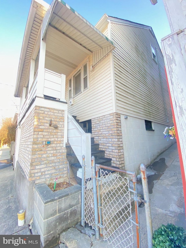 view of side of home with a gate, brick siding, and fence