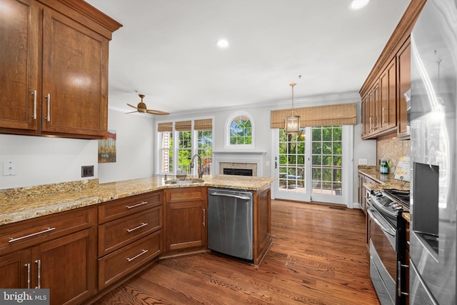 4637 Kirkland Pl, Alexandria, VA 22311 - kitchen featuring appliances with stainless steel finishes, a fireplace, a sink, dark wood-style flooring, and a peninsula