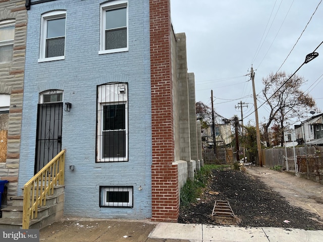 exterior space with entry steps, brick siding, and fence