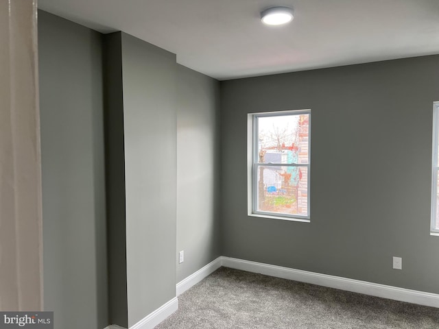 carpeted empty room featuring baseboards