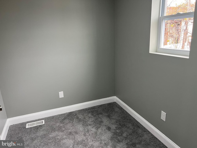 empty room featuring dark colored carpet, visible vents, and baseboards