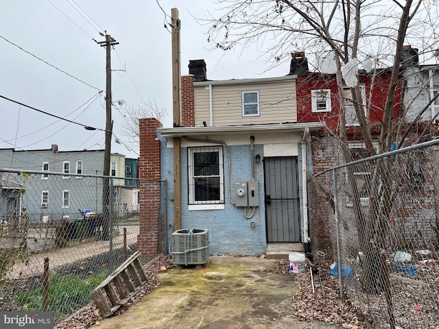 rear view of house featuring central air condition unit, fence private yard, a chimney, and brick siding