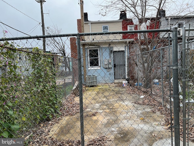 rear view of property with central AC unit, a chimney, fence, and brick siding