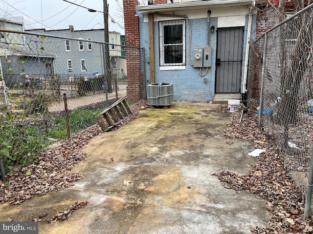 view of exterior entry with central air condition unit, fence, and brick siding