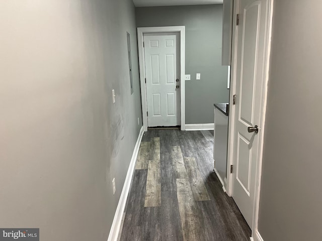 corridor with dark wood-type flooring and baseboards