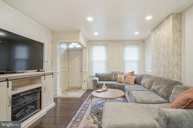 living room featuring dark wood finished floors, a decorative wall, and recessed lighting