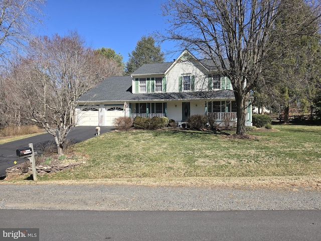 traditional-style house featuring a porch, a front lawn, a garage, and aphalt driveway