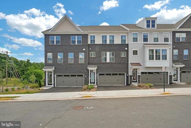 townhome / multi-family property with driveway, brick siding, and an attached garage