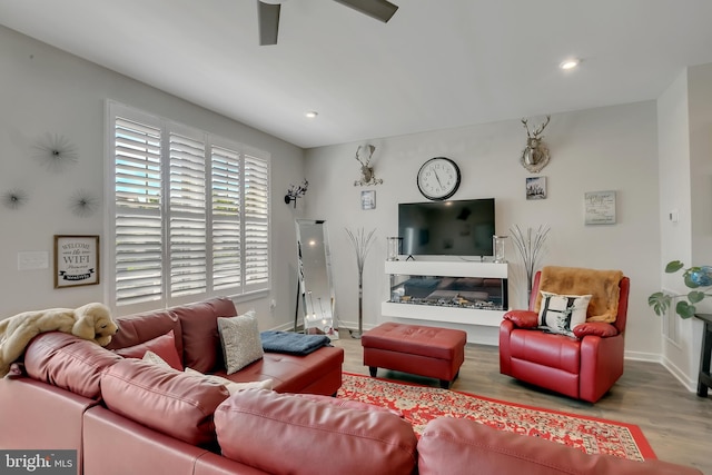 living area with wood finished floors, recessed lighting, a glass covered fireplace, and baseboards