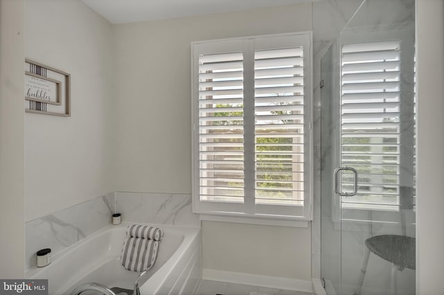 bathroom with a garden tub, baseboards, and a stall shower