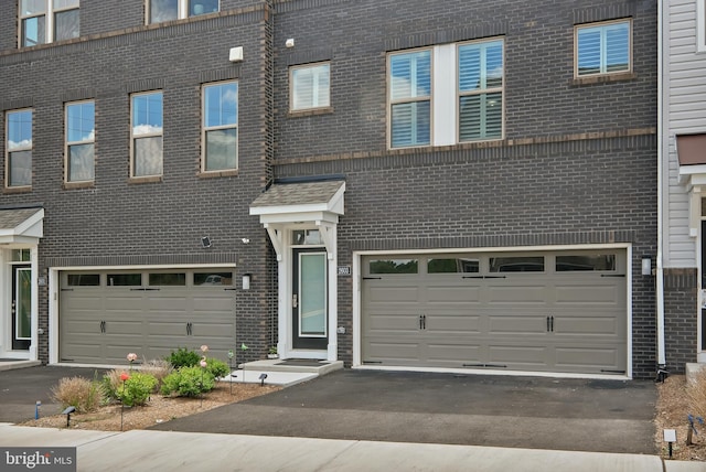 view of property featuring a garage, driveway, and brick siding