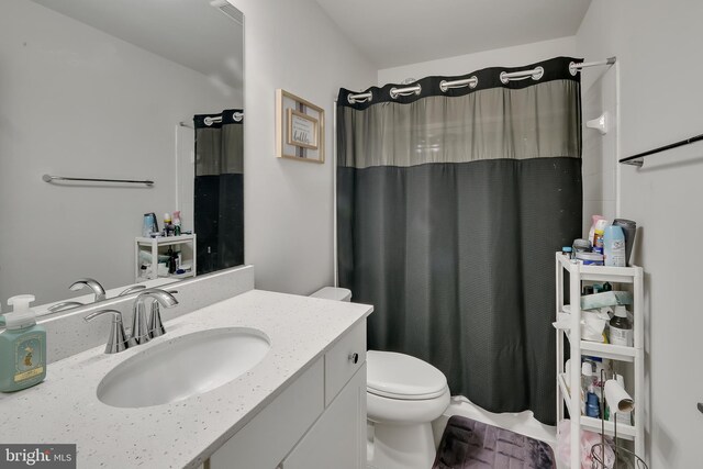 full bathroom featuring a shower with shower curtain, vanity, and toilet