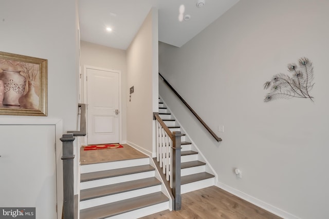 staircase with baseboards and wood finished floors