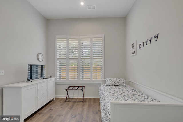 bedroom with baseboards, visible vents, and wood finished floors