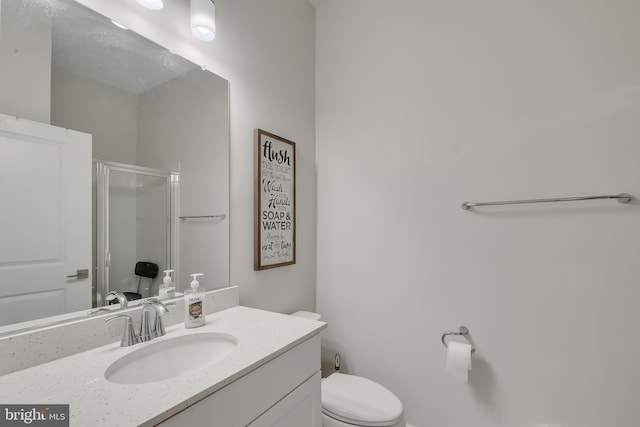 full bathroom featuring a stall shower, vanity, and toilet