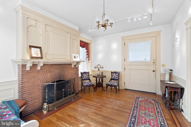 foyer entrance featuring a chandelier, rail lighting, a wainscoted wall, and light wood-style flooring