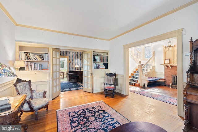 interior space with built in features, french doors, a wainscoted wall, ornamental molding, and wood finished floors