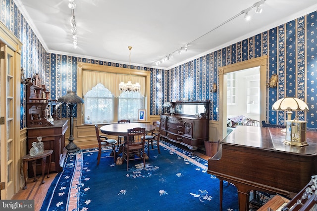 dining room featuring a wainscoted wall, wood finished floors, rail lighting, and wallpapered walls