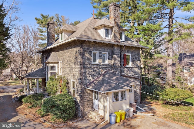 view of side of property featuring stone siding and a chimney