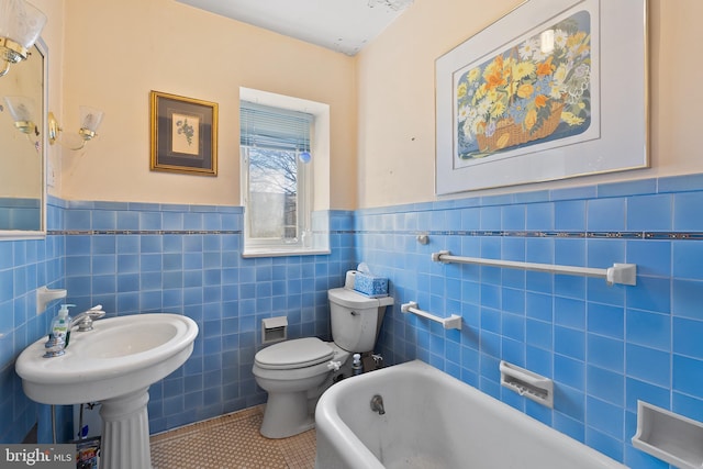 bathroom with tile patterned flooring, a freestanding tub, a wainscoted wall, and toilet