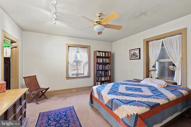 bedroom featuring ceiling fan, baseboards, and light colored carpet