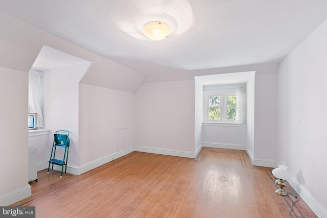 additional living space with vaulted ceiling, baseboards, and wood finished floors