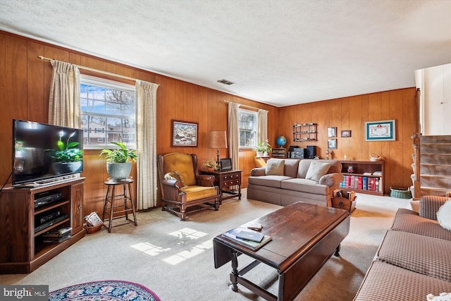 living room featuring visible vents, carpet, stairs, and a textured ceiling