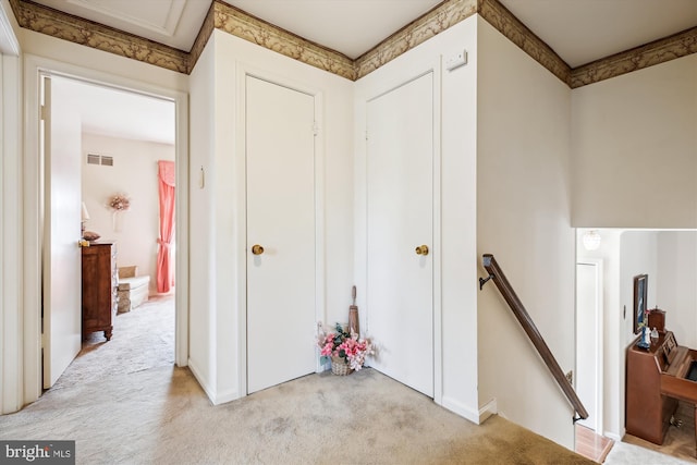 hallway with light carpet, an upstairs landing, and visible vents