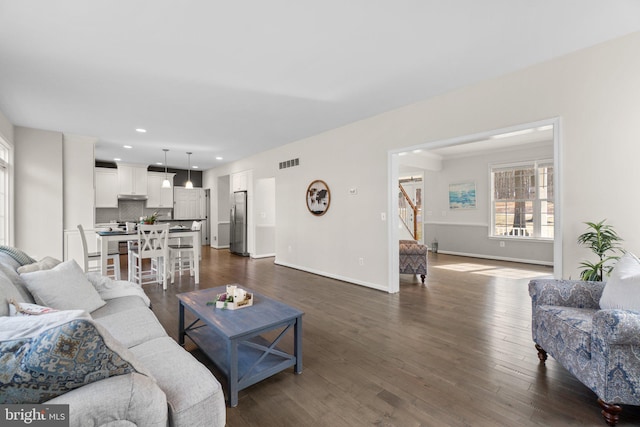 living area featuring baseboards, visible vents, stairway, dark wood-type flooring, and recessed lighting