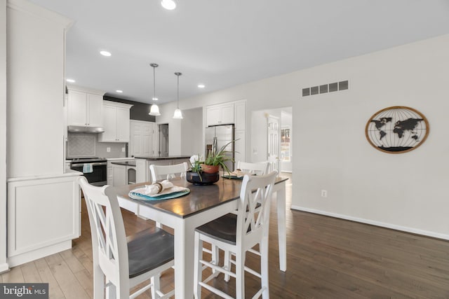 dining room with baseboards, visible vents, wood finished floors, and recessed lighting