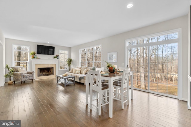 dining room with a wealth of natural light, a fireplace, visible vents, and hardwood / wood-style floors