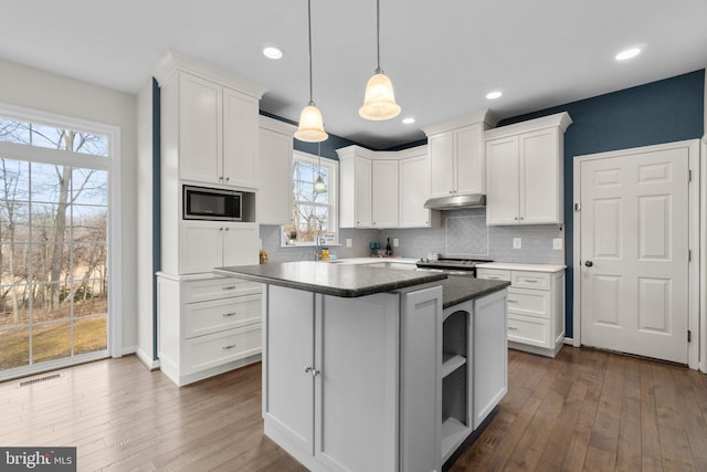 kitchen featuring under cabinet range hood, electric range, visible vents, white cabinets, and built in microwave