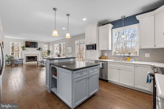 kitchen featuring dark wood-style flooring, a center island, a sink, stainless steel appliances, and backsplash