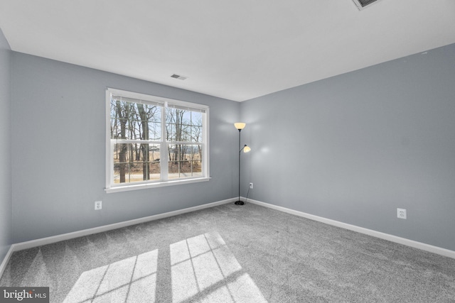 carpeted spare room featuring visible vents and baseboards