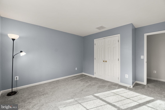 unfurnished bedroom with a closet, carpet, visible vents, and baseboards