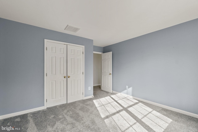 unfurnished bedroom with a closet, carpet flooring, visible vents, and baseboards