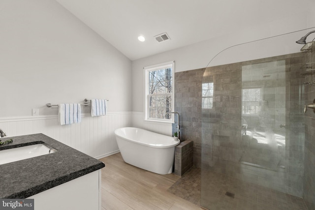 full bath featuring a wainscoted wall, vaulted ceiling, a tile shower, and visible vents