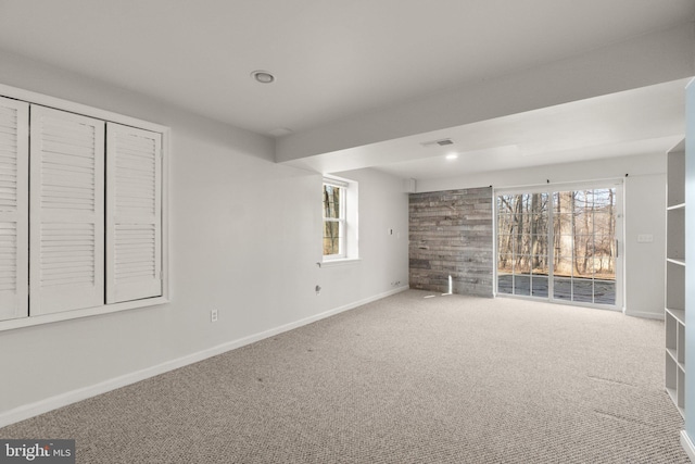 unfurnished living room with visible vents, baseboards, carpet, wood walls, and recessed lighting