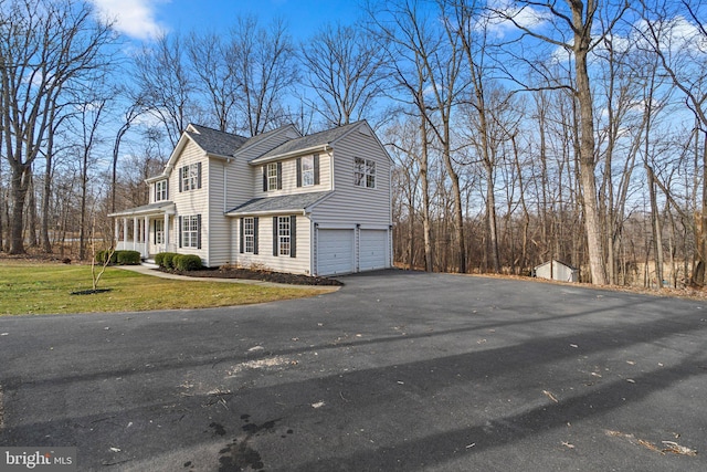 view of home's exterior featuring aphalt driveway, roof with shingles, a lawn, and a garage