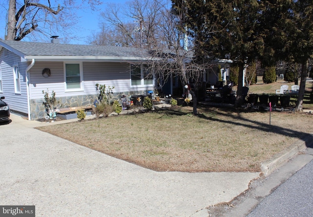 ranch-style home with a chimney, a front lawn, and a shingled roof