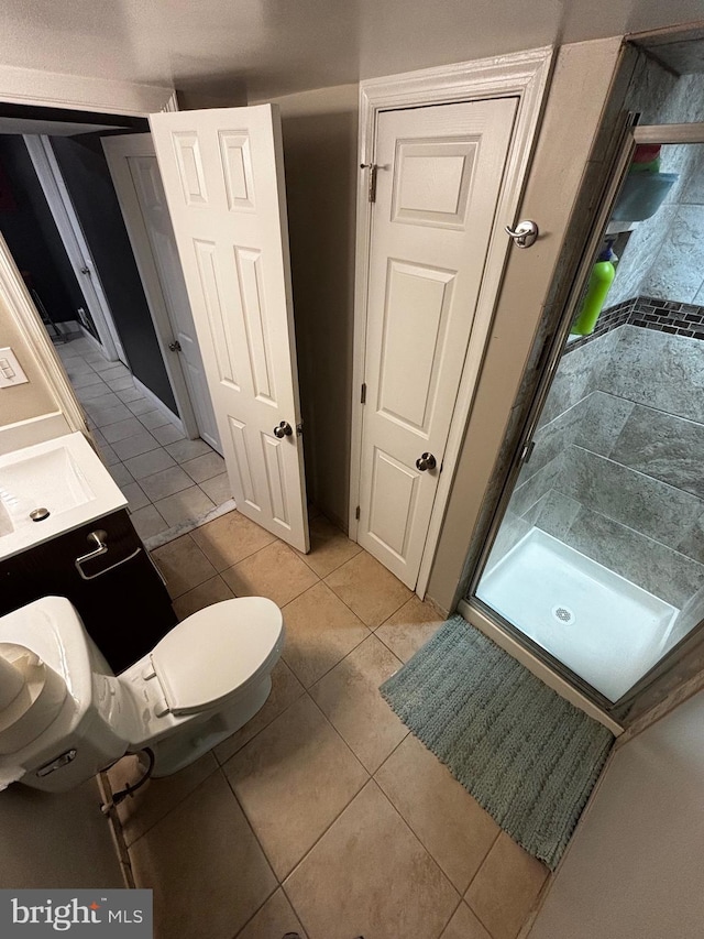 bathroom with tile patterned flooring, toilet, and a stall shower