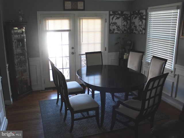 dining space with a decorative wall, wainscoting, french doors, and wood finished floors