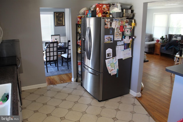 kitchen featuring light wood-type flooring, plenty of natural light, stainless steel fridge with ice dispenser, and crown molding