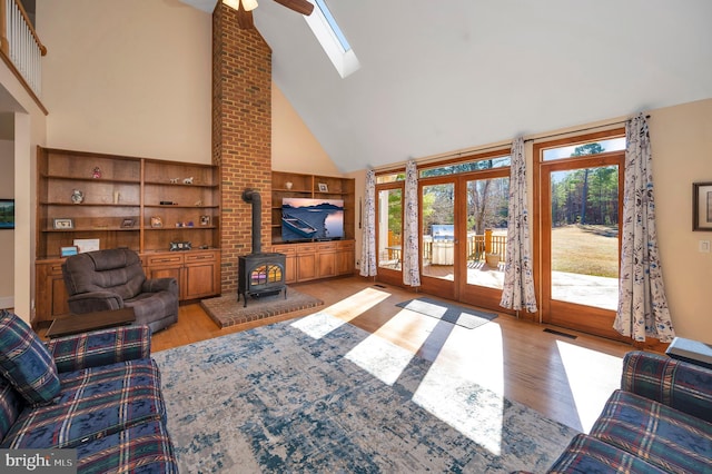 living room featuring visible vents, a wood stove, wood finished floors, and a wealth of natural light