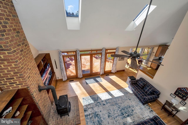 living area featuring french doors, ceiling fan, wood finished floors, vaulted ceiling with skylight, and baseboards