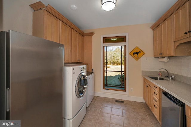 washroom with washing machine and clothes dryer, visible vents, light tile patterned flooring, a sink, and laundry area